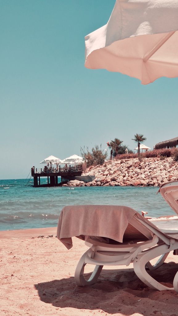 A peaceful beach view featuring sun loungers and umbrellas, ideal for a summer vacation.
