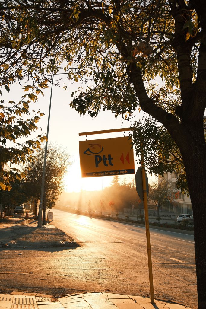 Sunset light glows on an urban street with Ptt sign, enhancing evening mood.